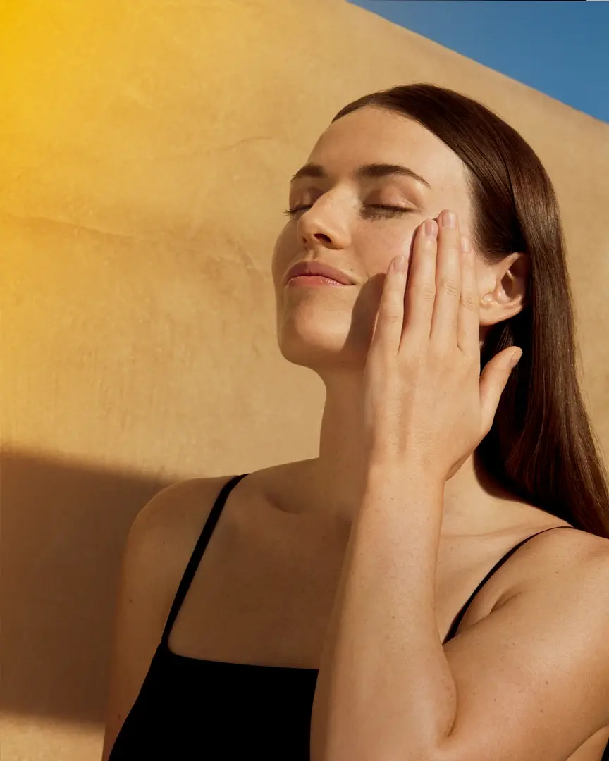 Heliocare Sonnenschutz für den Sommer EIne Frau cremt sich das Gesicht ein